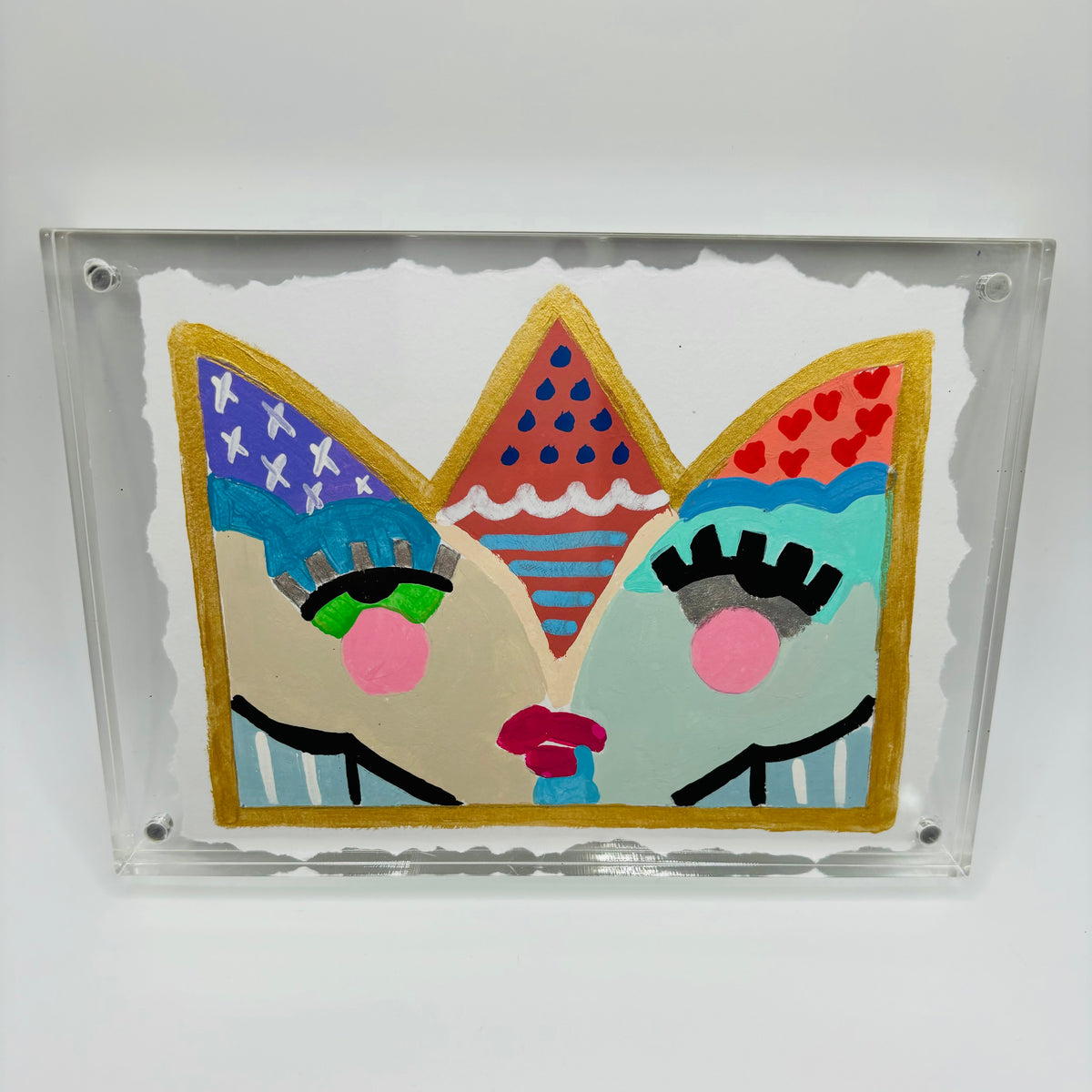 A square acrylic wall art piece featuring a colorful, whimsical cat face design inside a clear acrylic frame, mounted on a white wall.