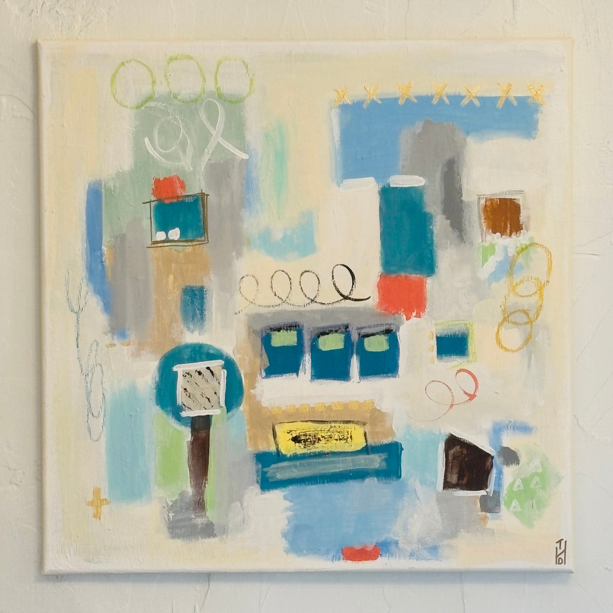 An abstract expressionist painting on canvas featuring a mix of blue, green, yellow, red, and gray brushstrokes on a cream background, hung on a textured white wall.