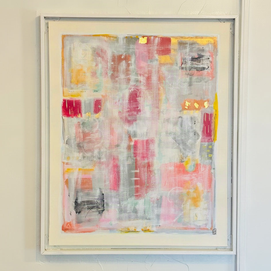 An abstract framed painting featuring a textured collage of pink, gray, white, yellow, and red brushstrokes, mounted on a textured white wall.